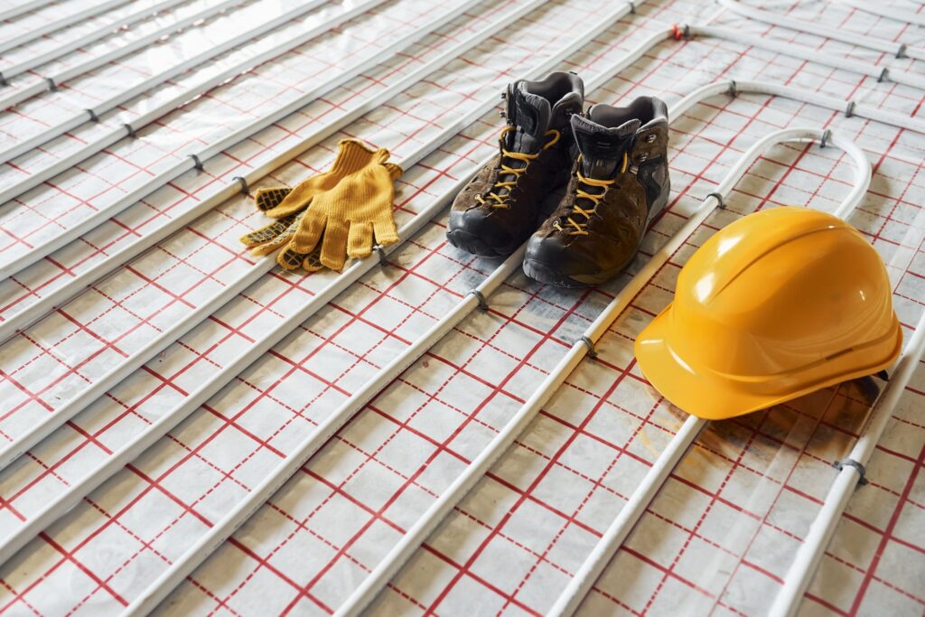 A wet underfloor heating system with the installer’s gloves, boots and hat. The customer has considered water underfloor heating vs. electric heating system.