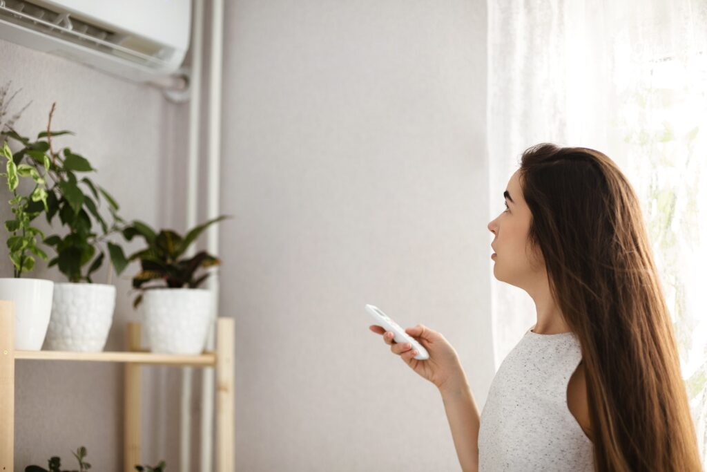 A woman in her home using a split system home air conditioner.