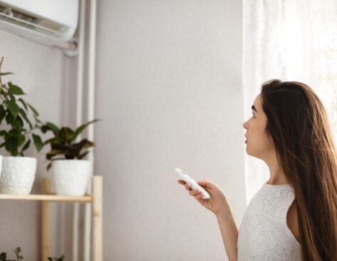 A woman in her home using a split system home air conditioner.