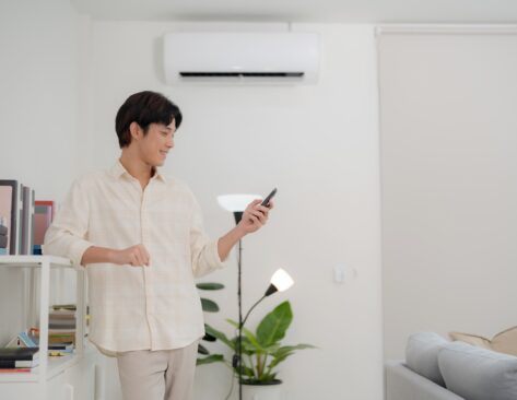 Young man in a casual shirt figuring out how home air conditioning works