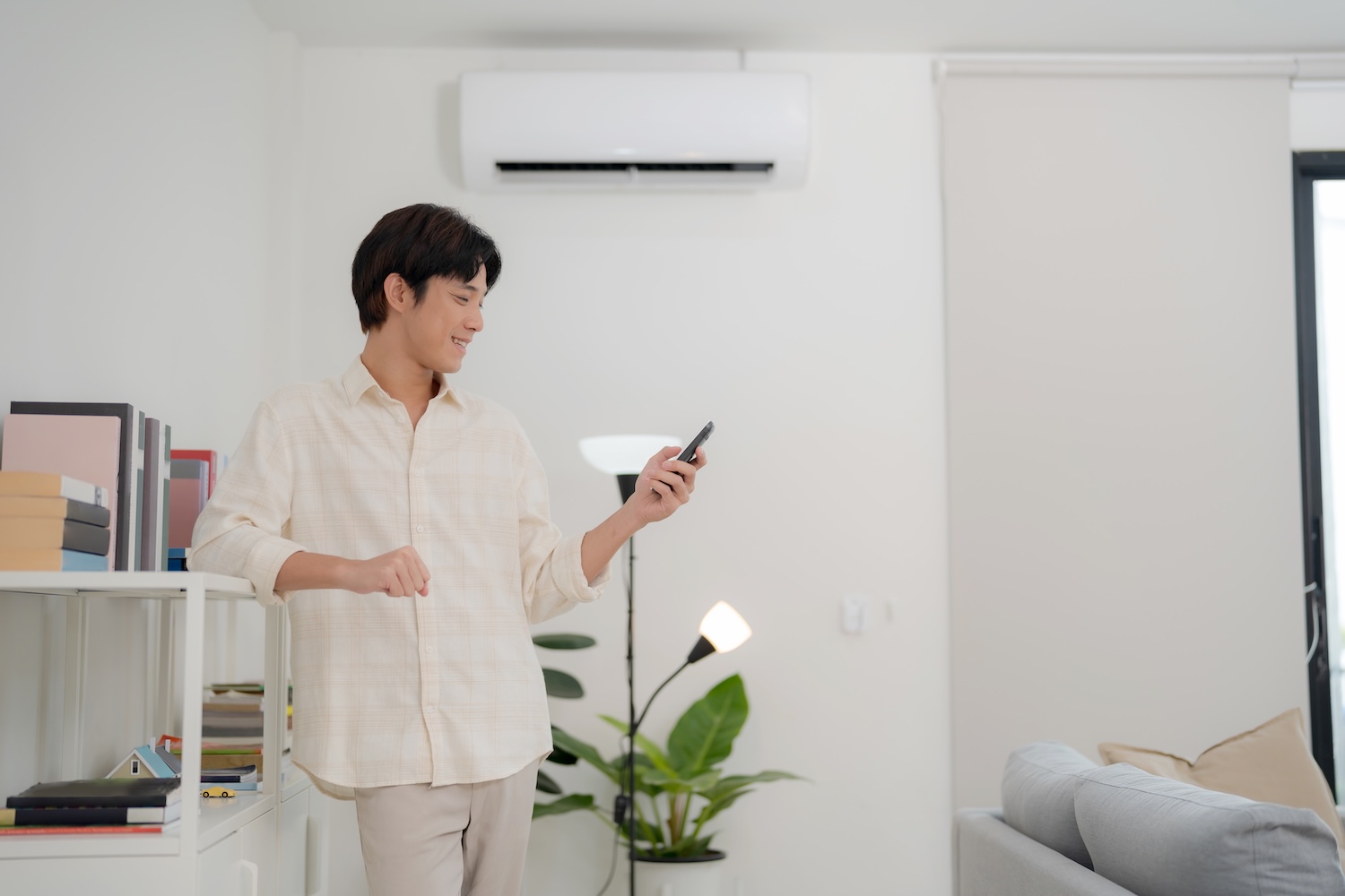 Young man in a casual shirt figuring out how home air conditioning works